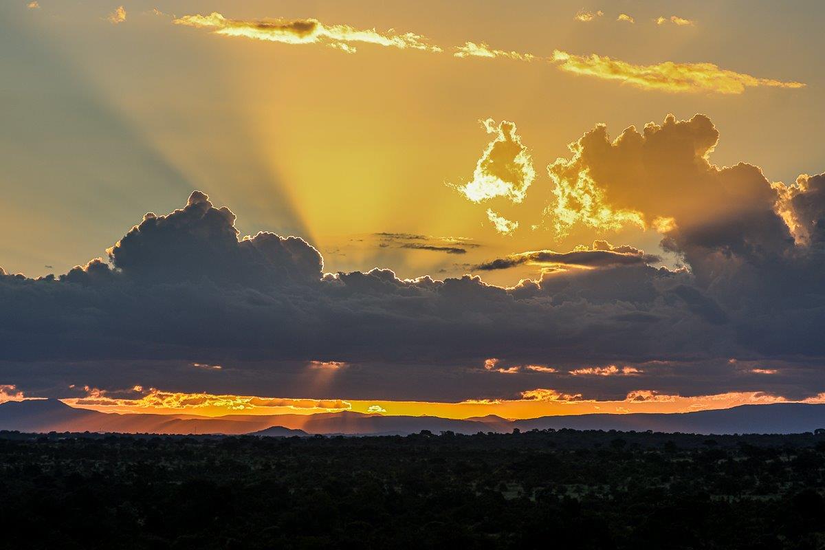 The sun's rays peaking through the clouds as it sets beyond the horizon. The sun's rays peaking through the clouds as it sets beyond the horizon.
