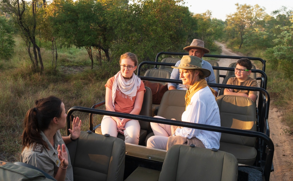 Engaged family absorbs guide's wisdom on private game drive. Engaged family absorbs guide's wisdom on private game drive.