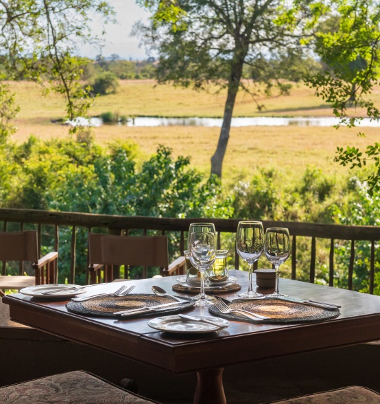 Sabi Sabi guests dine on deck overlooking the watering hole at the Bush Lodge.